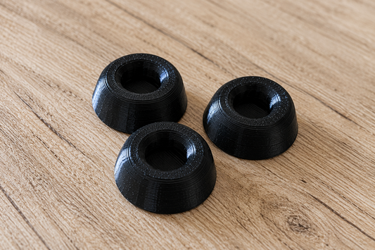 Three black SICLab replacement feet arranged on a wooden surface